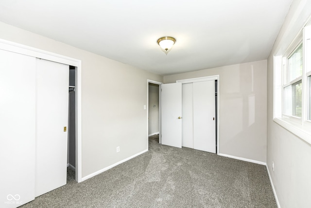 unfurnished bedroom with baseboards, carpet, and two closets