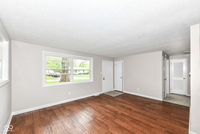 interior space featuring dark wood-style floors, a textured ceiling, and baseboards