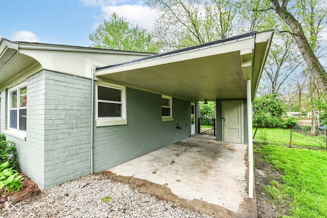 exterior space with brick siding, a front yard, and an attached carport