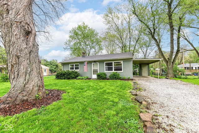 ranch-style house featuring a chimney, gravel driveway, brick siding, an attached carport, and a front lawn