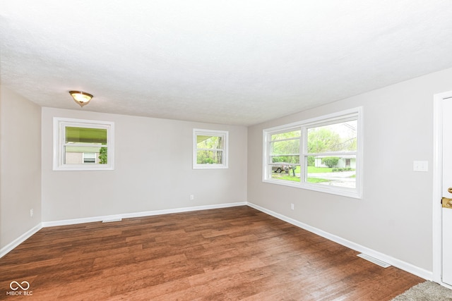 spare room with baseboards, visible vents, and wood finished floors