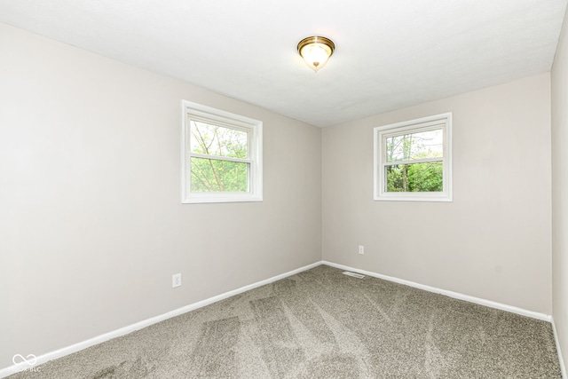 unfurnished room with carpet, visible vents, and baseboards