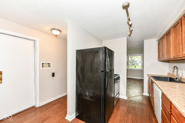 kitchen featuring a sink, white dishwasher, freestanding refrigerator, dark wood-type flooring, and brown cabinetry