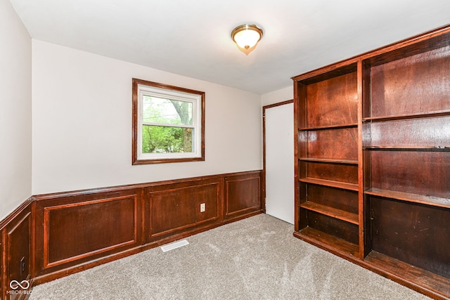 carpeted spare room with a wainscoted wall and visible vents