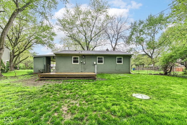 rear view of property with brick siding, fence, a wooden deck, and a yard