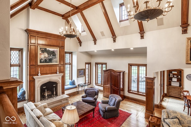 living area with high vaulted ceiling, an inviting chandelier, a wealth of natural light, and light wood-style flooring