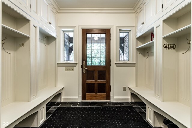 mudroom featuring crown molding, baseboards, and dark tile patterned flooring