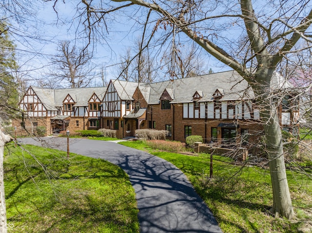 tudor-style house featuring a balcony and brick siding