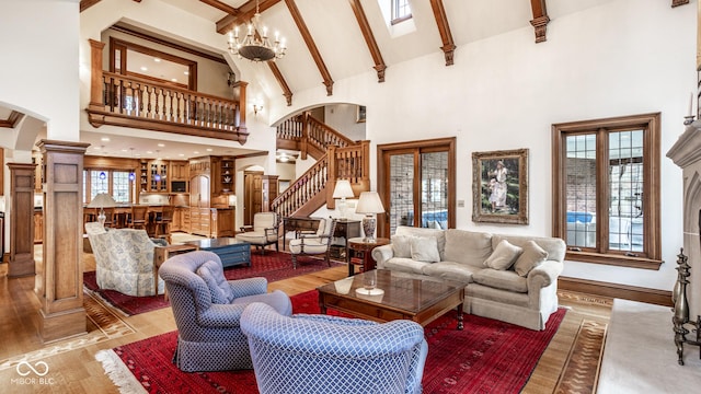 living area featuring arched walkways, beam ceiling, high vaulted ceiling, light wood finished floors, and stairs