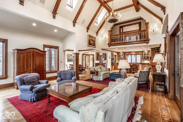 living room with an inviting chandelier, arched walkways, high vaulted ceiling, decorative columns, and wood finished floors