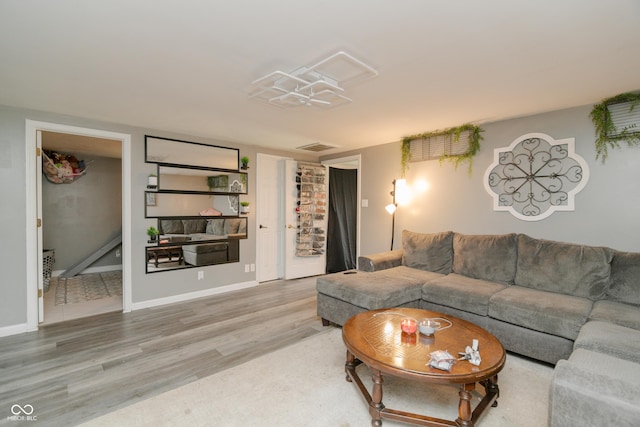 living room featuring baseboards, light wood finished floors, and visible vents