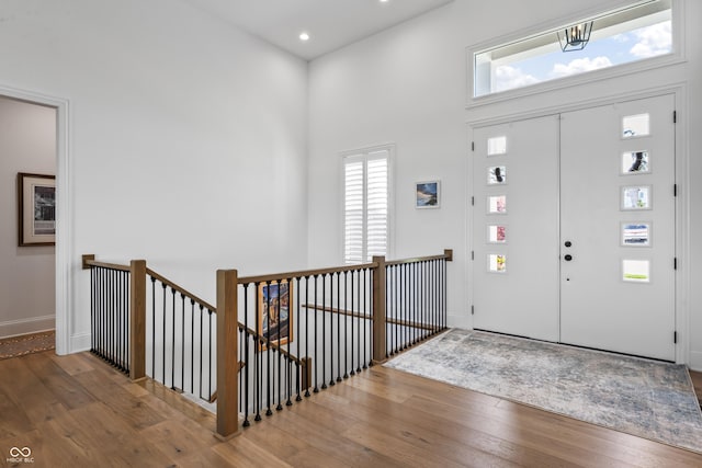 foyer entrance featuring plenty of natural light, a high ceiling, hardwood / wood-style flooring, and a notable chandelier
