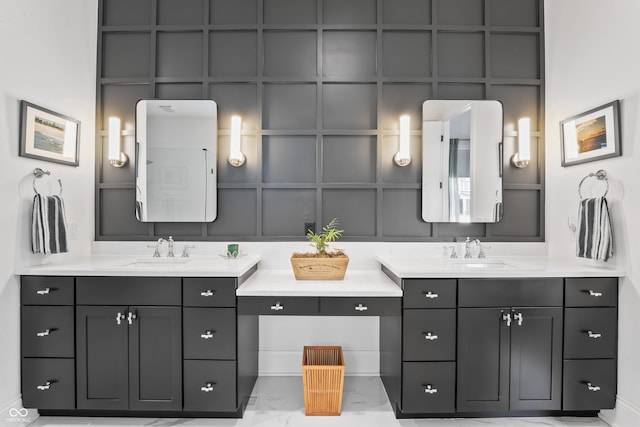 full bath with two vanities, a sink, marble finish floor, and a decorative wall