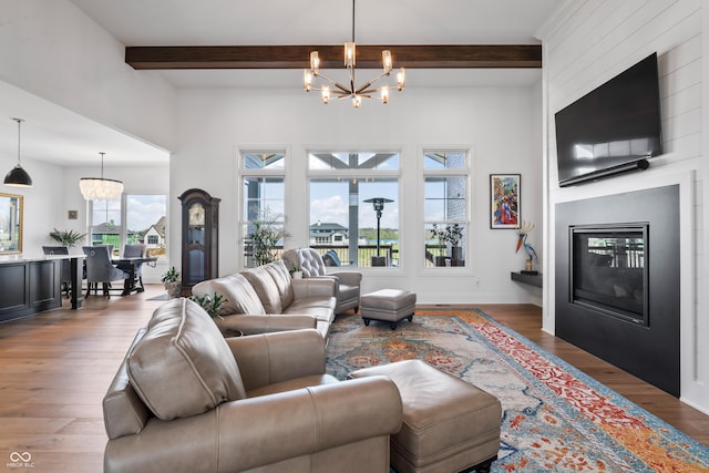 living room featuring wood finished floors, beam ceiling, a chandelier, and a large fireplace