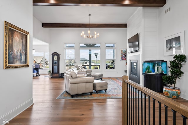 living area featuring an inviting chandelier, wood-type flooring, baseboards, beamed ceiling, and visible vents