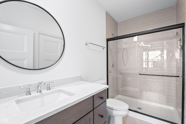 bathroom featuring vanity, a shower stall, and toilet