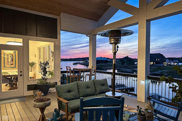 deck at dusk with a water view and an outdoor hangout area