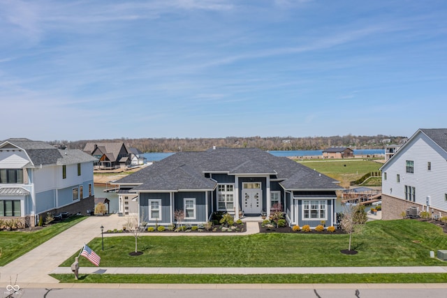 ranch-style home with a shingled roof, board and batten siding, driveway, and a front yard