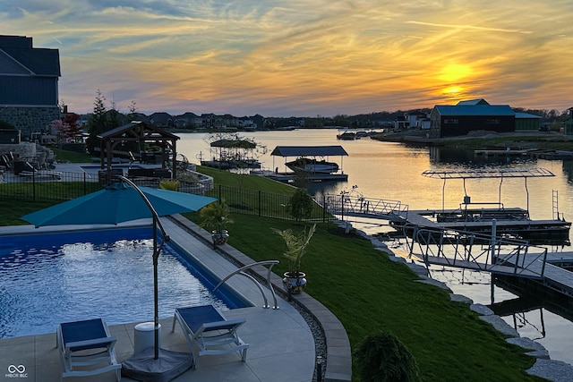pool at dusk featuring a water view, fence, and a boat dock