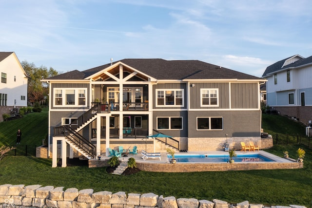 rear view of house featuring a lawn, a wooden deck, stairway, a fenced in pool, and a patio