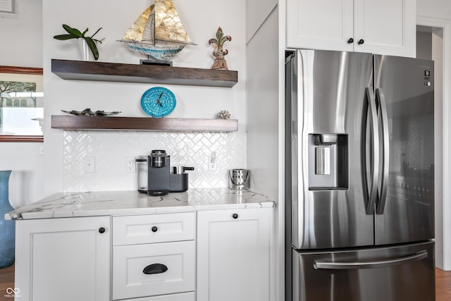 interior space with tasteful backsplash, open shelves, light stone countertops, white cabinets, and stainless steel fridge