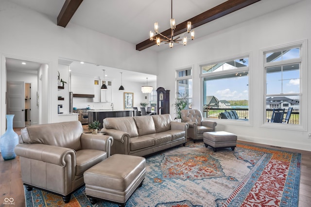living area featuring an inviting chandelier, baseboards, dark wood finished floors, and beam ceiling