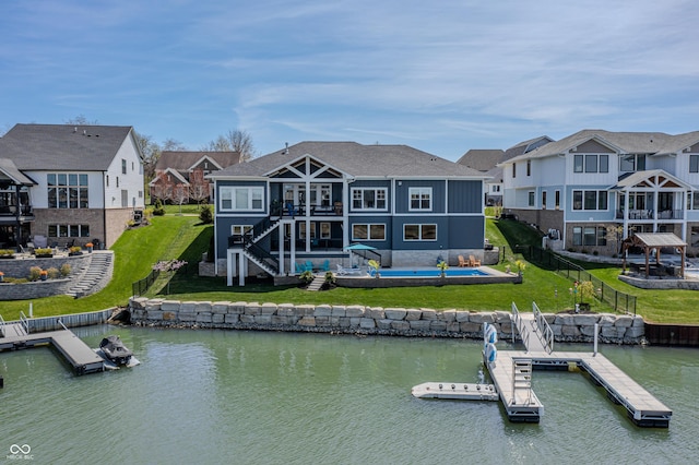 rear view of property with a residential view, stairway, a fenced backyard, a water view, and a yard