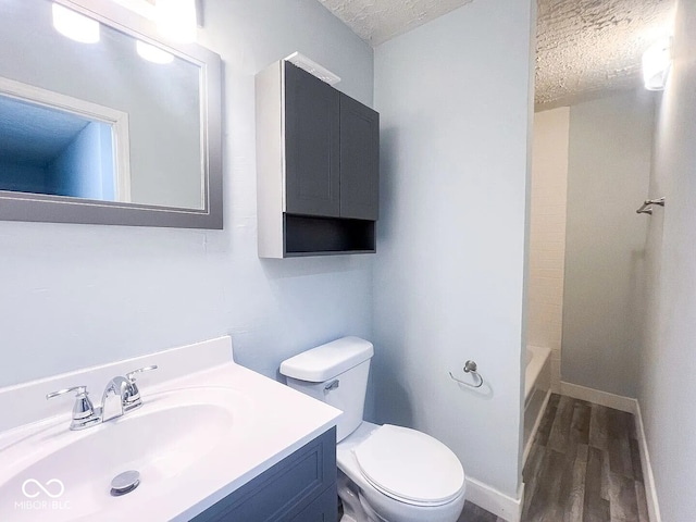 full bath featuring toilet, a textured ceiling, wood finished floors, and vanity