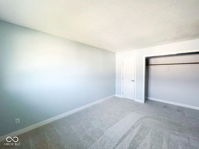 unfurnished bedroom with a textured ceiling, a closet, carpet, and baseboards