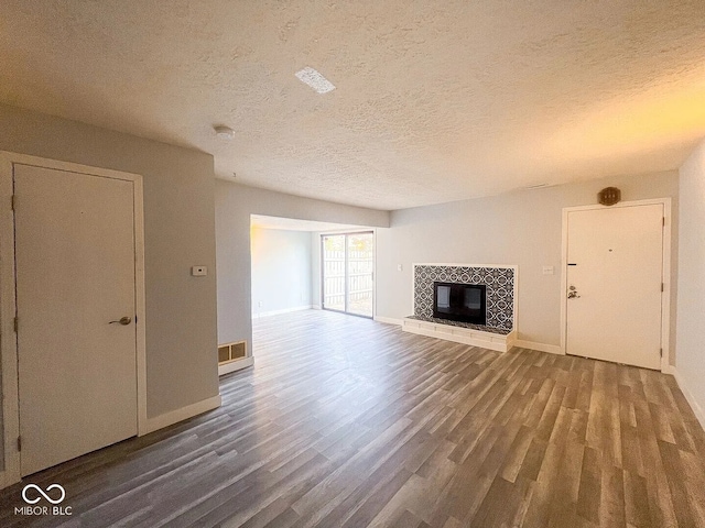 unfurnished living room with wood finished floors, visible vents, baseboards, and a textured ceiling