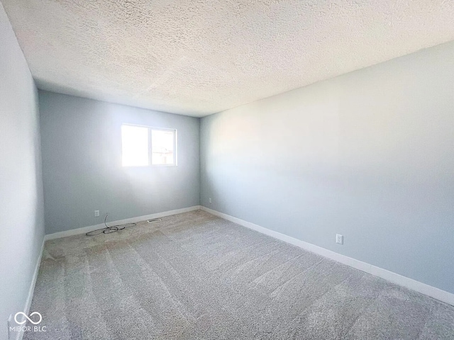 spare room featuring a textured ceiling, carpet flooring, and baseboards