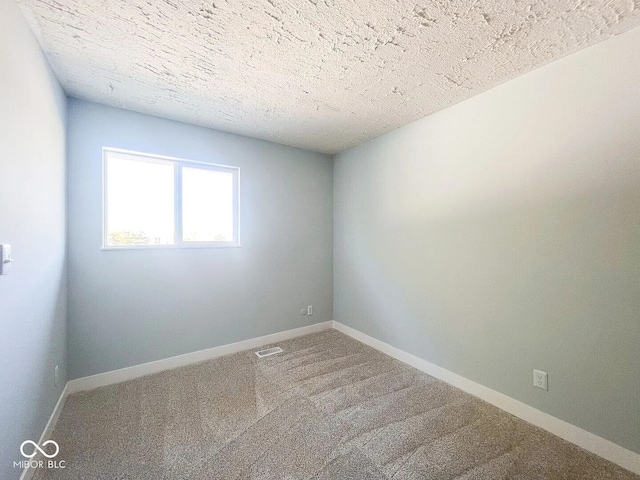 carpeted spare room featuring a textured ceiling, visible vents, and baseboards