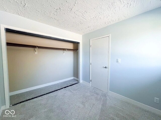unfurnished bedroom with a closet, a textured ceiling, and baseboards