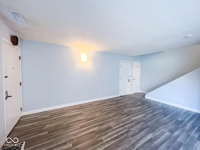 unfurnished living room with dark wood finished floors, baseboards, and visible vents