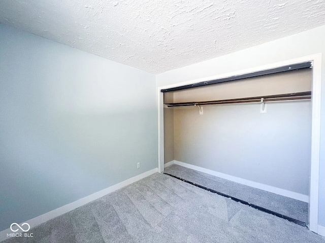 unfurnished bedroom with a textured ceiling, a closet, baseboards, and carpet floors