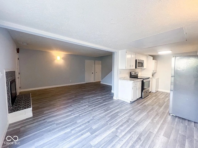 kitchen with baseboards, wood finished floors, a textured ceiling, and appliances with stainless steel finishes
