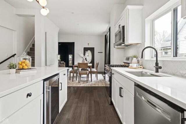 629 N Keystone Ave, Indianapolis, IN 46201 - kitchen featuring appliances with stainless steel finishes, beverage cooler, a sink, white cabinetry, and decorative backsplash