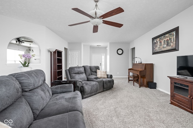 living room featuring carpet floors, a ceiling fan, baseboards, and a textured ceiling