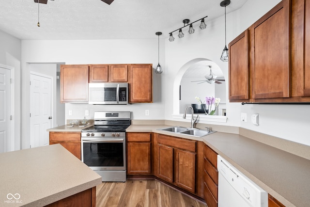 kitchen featuring a sink, ceiling fan, stainless steel appliances, and brown cabinets