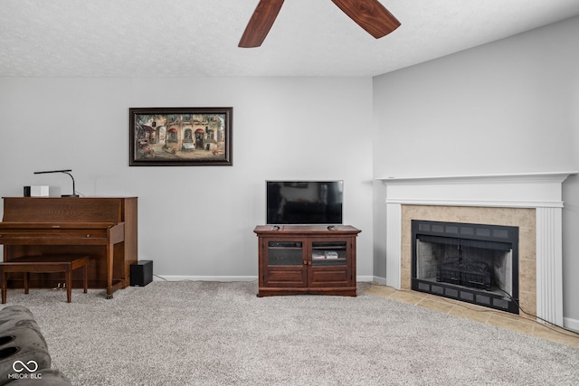 carpeted living area featuring a tiled fireplace, baseboards, and ceiling fan