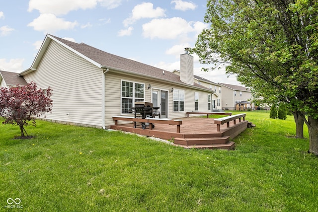 back of house featuring a yard, a wooden deck, roof with shingles, and a chimney