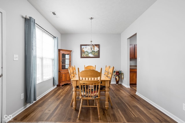 dining space featuring baseboards, dark wood finished floors, an inviting chandelier, and visible vents