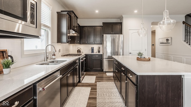 14878 Anees Ln, Fishers, IN 46040 - kitchen featuring premium appliances, a sink, crown molding, dark wood-type flooring, and a kitchen island