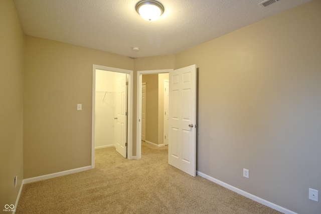 6634 Frankenberger Dr, Indianapolis, IN 46237 - unfurnished bedroom with a walk in closet, light carpet, and a textured ceiling