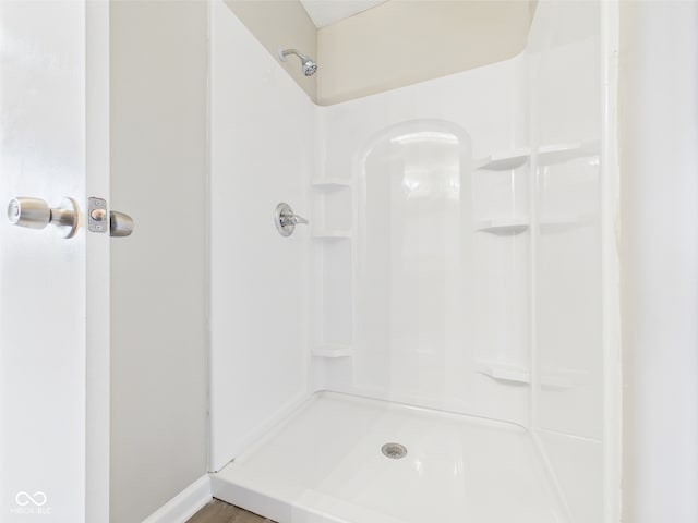 bathroom featuring baseboards, walk in shower, and wood finished floors