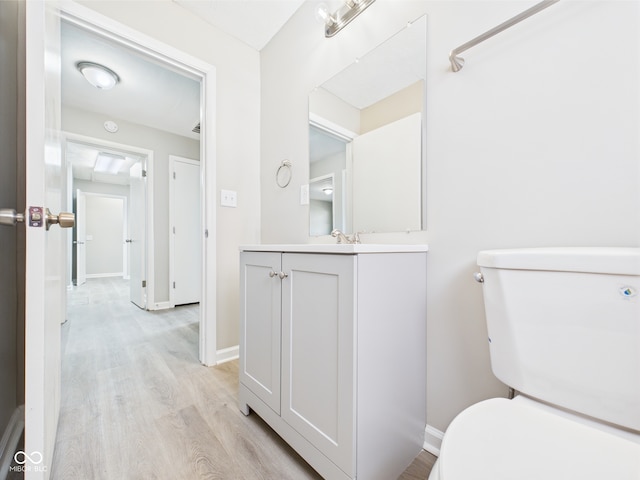 half bath with vanity, toilet, and wood finished floors