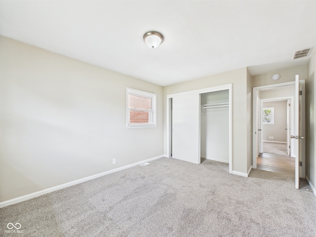 unfurnished bedroom featuring baseboards, multiple windows, carpet flooring, and visible vents