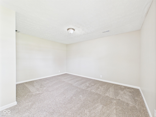 carpeted spare room with baseboards, a textured ceiling, and visible vents