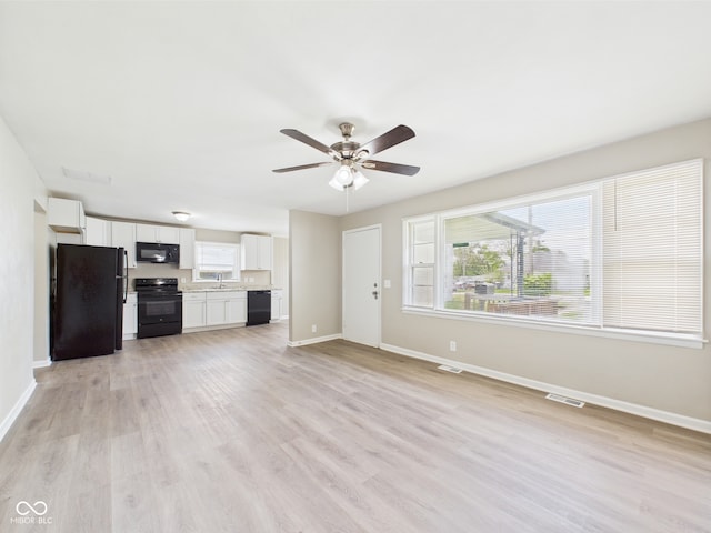 unfurnished living room featuring baseboards, a wealth of natural light, ceiling fan, and visible vents