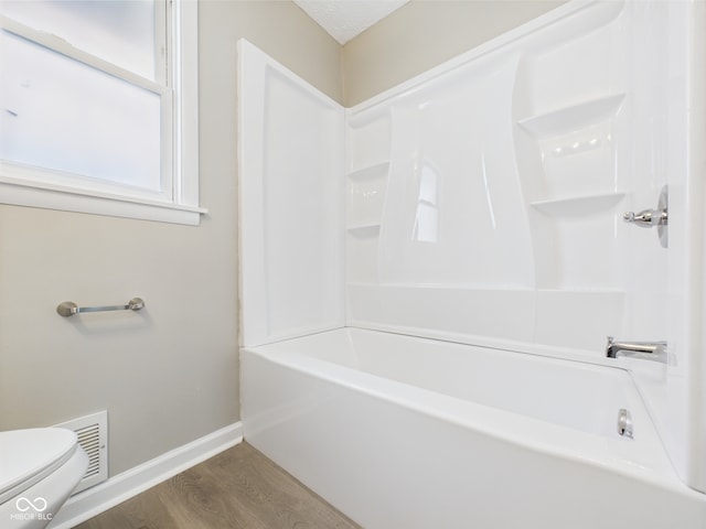 bathroom featuring visible vents, wood finished floors, baseboards, toilet, and shower / bathtub combination